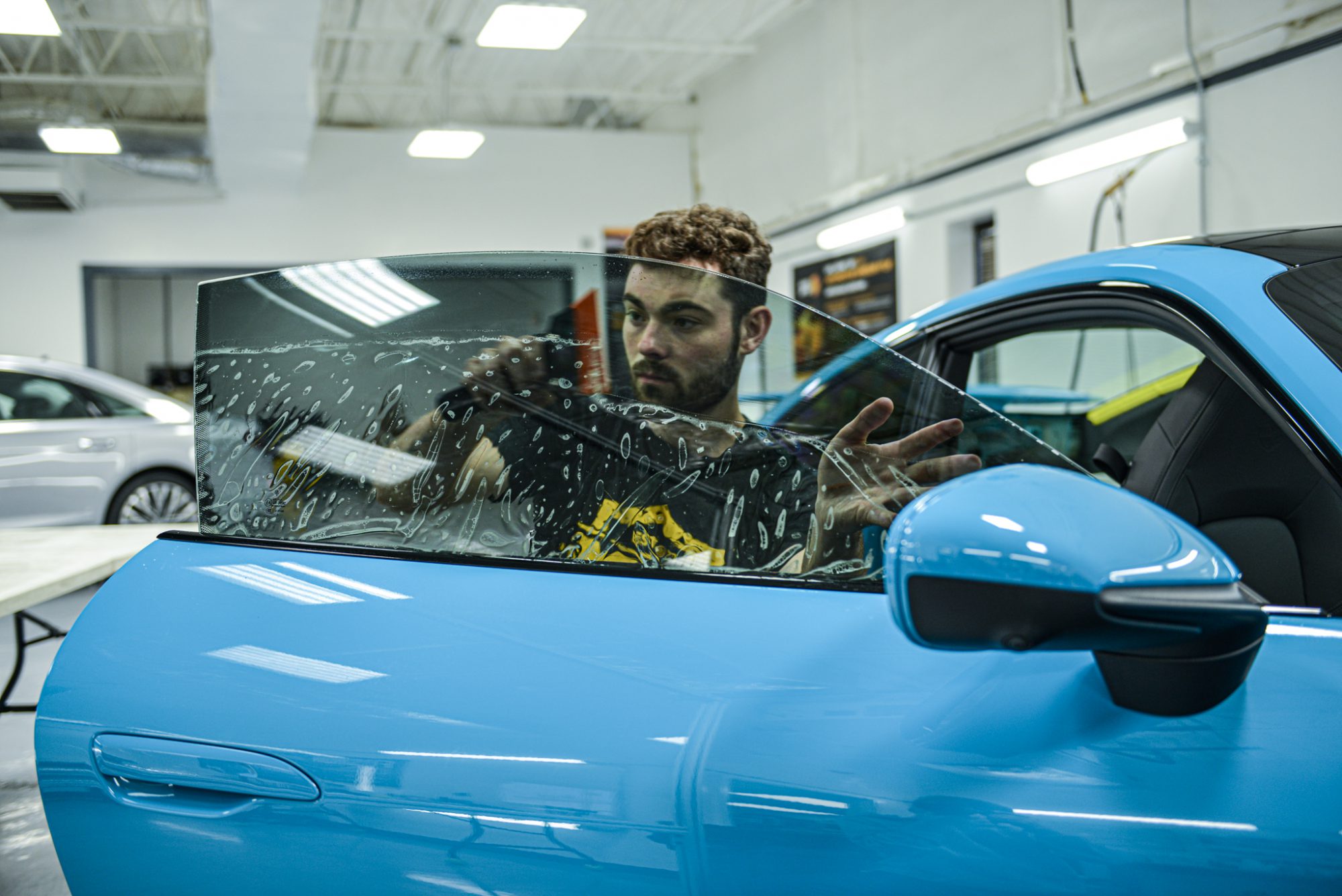 IMG_6349 a technician installing window tint on a blue sports car
